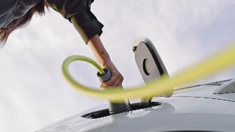 
Eine Hand steckt ein Ladekabel in ein Elektroauto.