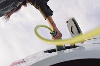 
Eine Hand steckt ein Ladekabel in ein Elektroauto.