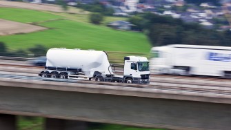 
Schnell fahrender weißer Lkw mit Anhänger auf einer Autobahn