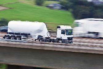 
Schnell fahrender weißer Lkw mit Anhänger auf einer Autobahn