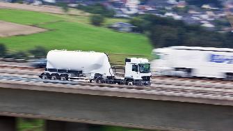 
Schnell fahrender weißer Lkw mit Anhänger auf einer Autobahn