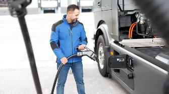 
Mann lädt einen elektrischen Lkw an einer Ladestation