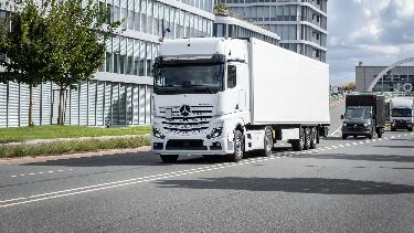 
Lkw fährt auf einer Straße vor modernen Bürogebäuden