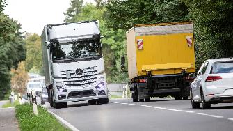 
Lkw und Autos fahren auf einer von Bäumen gesäumten Straße