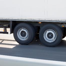 
Nahaufnahme der Räder eines fahrenden Lkw-Anhängers auf der Straße.