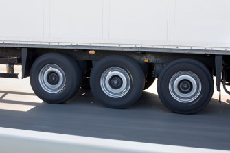 
Nahaufnahme der Räder eines fahrenden Lkw-Anhängers auf der Straße.