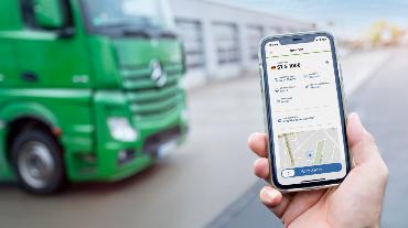 
Smartphone mit geöffneter TollNow App vor einem grünen Lkw