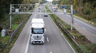 
Lkw fährt unter einer Kontrollbrücke auf einer Autobahn