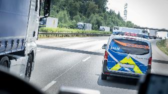 
Kontrollfahrzeug fährt neben einem Lkw auf einer mehrspurigen Autobahn