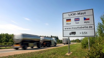 
Hinweisschild zur Lkw-Maut mit vorbeifahrendem Lkw auf einer Autobahn