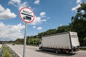 
Mautschild neben einer Straße mit vorbeifahrendem Lkw