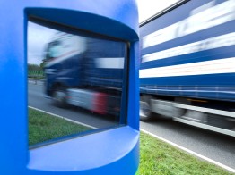 
Nahaufnahme einer Kontrollsäule mit Sichtfenster für die Kamera. Im Hintergrund fährt ein Lkw vorbei.