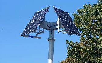 
Zwei Solarpaneele sind auf einem Mast montiert, vor blauem Himmel.