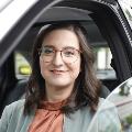 
Ariane Eberwein sitzt in einem Auto und blickt lächelnd aus dem geöffneten Fenster.