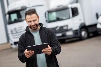 
Mann bedient ein Tablet vor mehreren geparkten Lkw