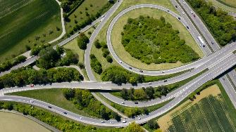 
Luftaufnahme eines Autobahnkreuzes mit mehreren Fahrbahnen und begrünten Flächen