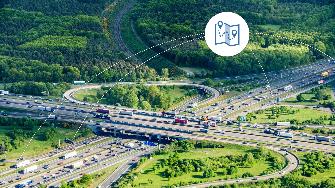 
Luftaufnahme eines stark befahrenen Autobahnkreuzes mit Icon für Navigation.
