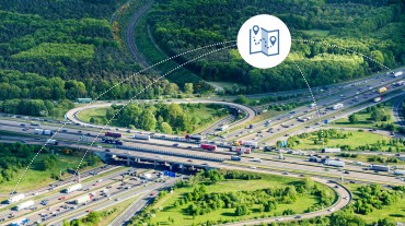 
Luftaufnahme eines stark befahrenen Autobahnkreuzes mit Icon für Navigation.