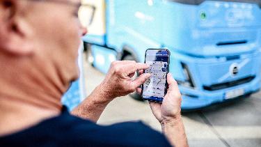 
Mann nutzt vor einem Lkw eine App, die die Auslastung von Lkw-Parkplätzen anzeigt