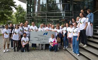 
Gruppe von Personen posiert vor dem Toll Collect Bürogebäude für ein Foto