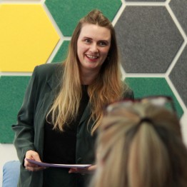 
Elina Penner steht lächelnd vor Publikum mit Dokument in der Hand