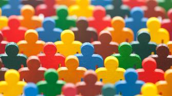 
Bunte Holzfiguren in Form von Menschen stehen dicht beieinander.