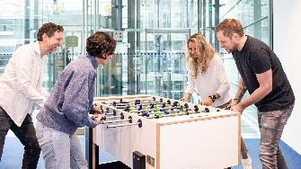 
Mehrere Mitarbeitende an Kickertisch