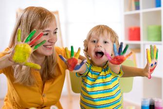 
Eine Frau und ein Kind halten ihre bunt bemalten Hände lächelnd in die Kamera.