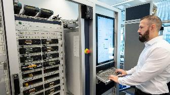 
Ein Mann arbeitet an einem Serverrack und nutzt ein integriertes Bedienpanel.