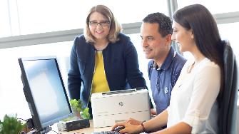 
Drei Mitarbeitende vor einem Bildschirm im Gespräch