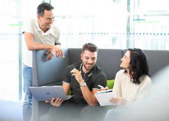 
Drei Mitarbeitende von Toll Collect im lockeren Austausch miteinander