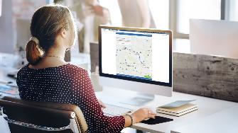 
Mitarbeiterin an einem Bildschirm mit Landkarte