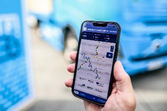 
Hand hält ein Smartphone mit einer Kartenansicht vor einem Lkw